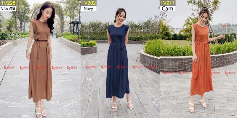 Ba người mẫu mặc váy dài với ba màu khác nhau: nâu đất, xanh navy và cam, đứng trên lối đi lát gạch.