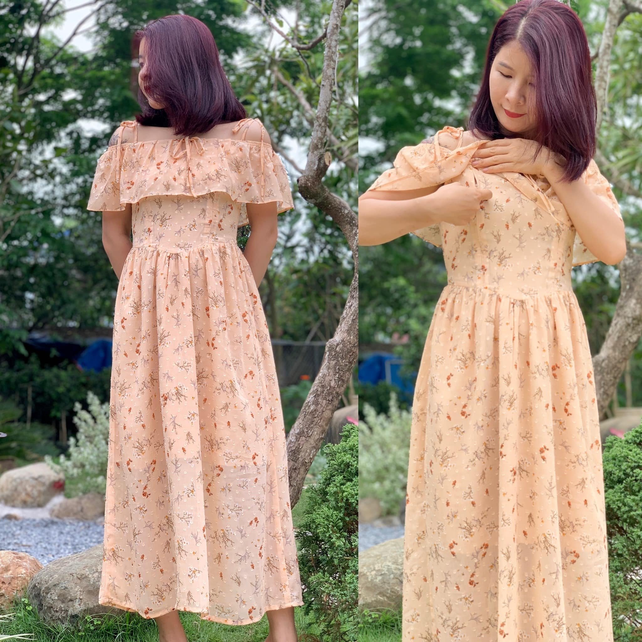 Người phụ nữ mặc váy hoa dài màu be đứng trong vườn, tay chỉnh sửa phần vai áo.