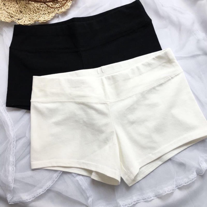 Hai chiếc quần đùi màu đen và trắng được đặt trên nền vải trắng và mũ rơm.