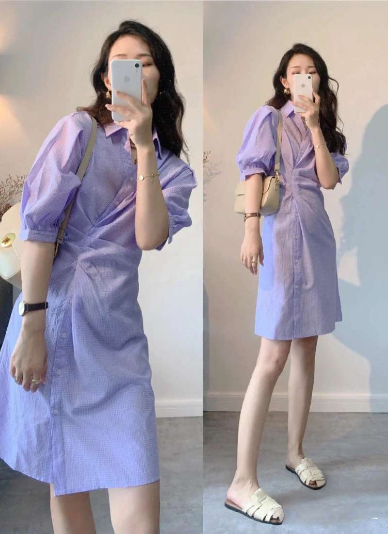 Người phụ nữ mặc váy tím, chụp ảnh tự sướng trước gương, đeo túi xách và đồng hồ.