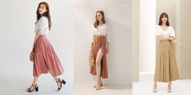 Ba người mặc áo trắng và chân váy dài màu sắc khác nhau, tạo kiểu dáng thời trang trong studio sáng sủa.