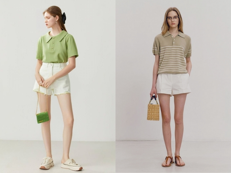Hai người mặc quần short trắng và áo polo xanh đứng trong không gian sáng, mỗi người cầm túi xách nhỏ.