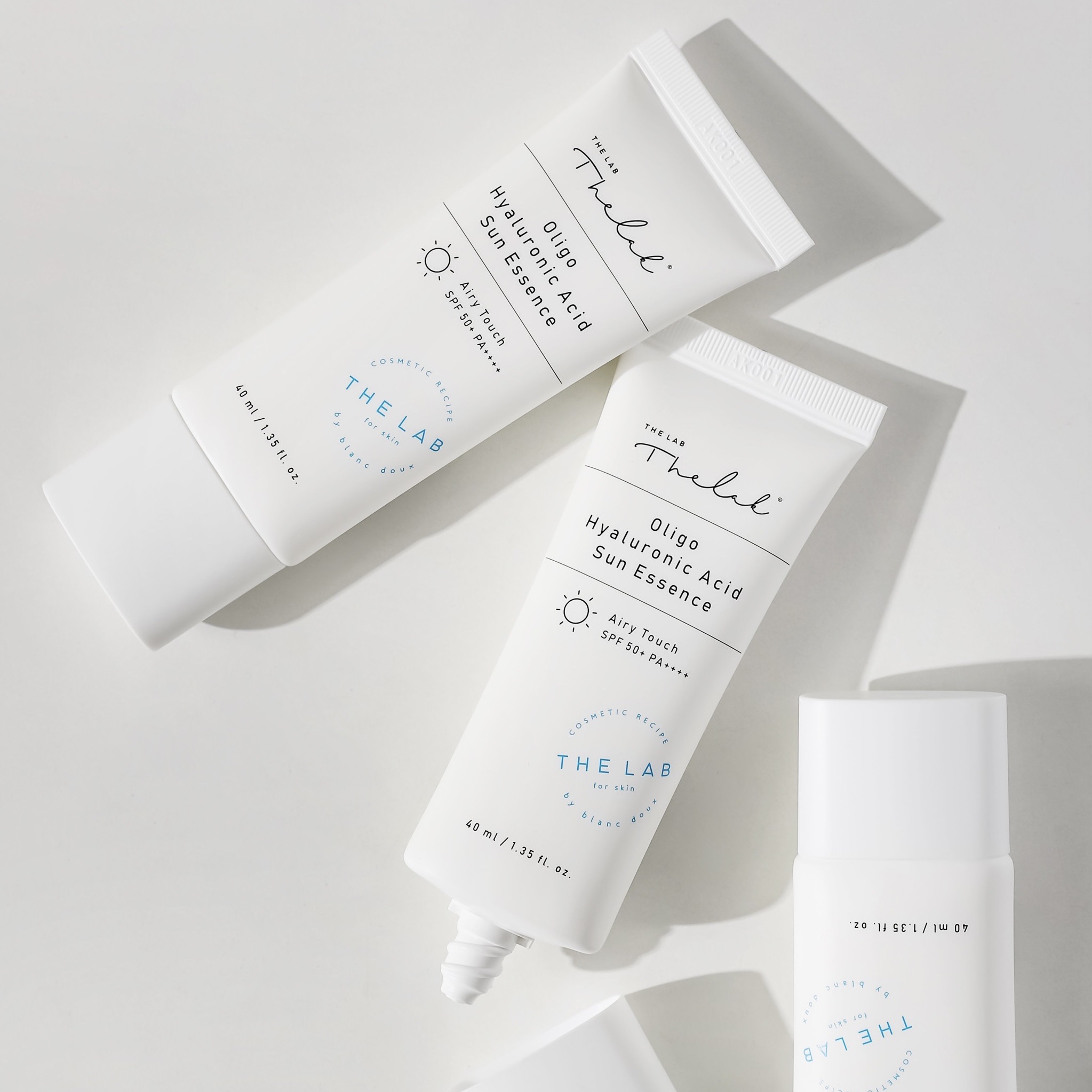 Ba tuýp kem chống nắng Oligo Hyaluronic Acid Sun Essence, màu trắng, nằm trên nền trắng.