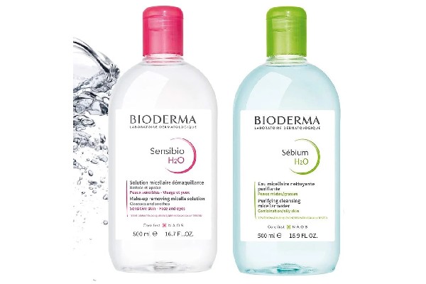 Hai chai nước tẩy trang Bioderma, một chai nắp hồng và một chai nắp xanh, dung tích 500 ml.
