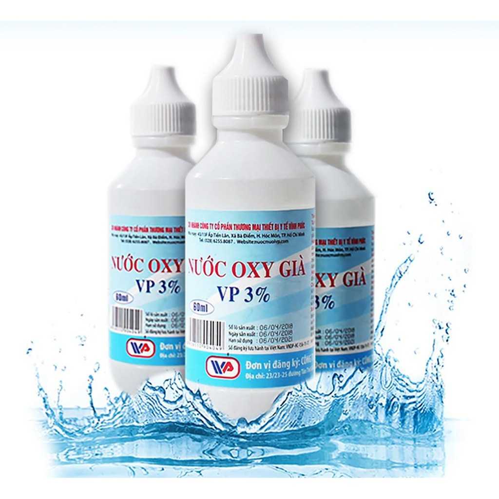 Ba chai nước oxy già VP 3% màu trắng với nhãn xanh, đứng trên nền nước bắn tung toé.