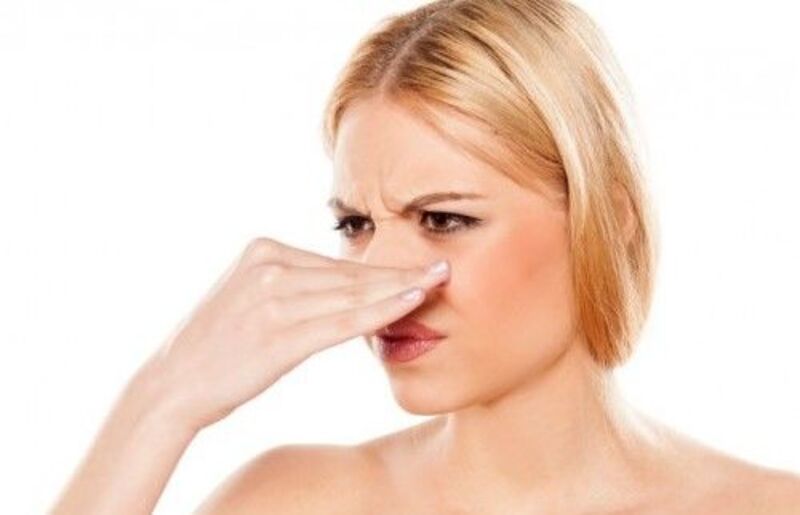 Người phụ nữ đang bịt mũi với biểu cảm khó chịu, có thể do mùi không dễ chịu.