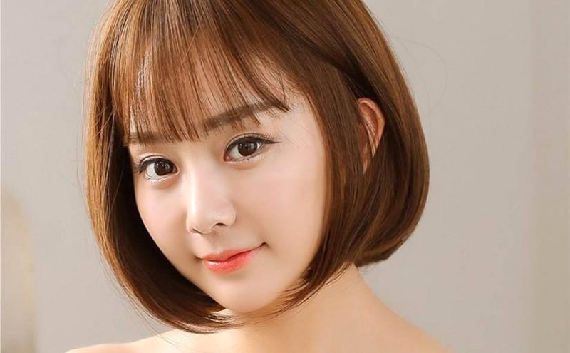 Người có tóc ngắn màu nâu, mái bằng, khuôn mặt nhìn về phía trước với biểu cảm nhẹ nhàng và phông nền màu sáng.