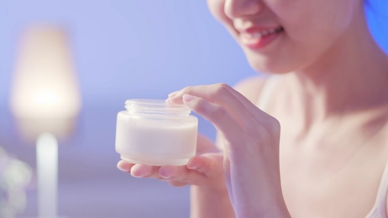Người cầm hũ kem dưỡng da, chuẩn bị lấy một ít sản phẩm từ bên trong.