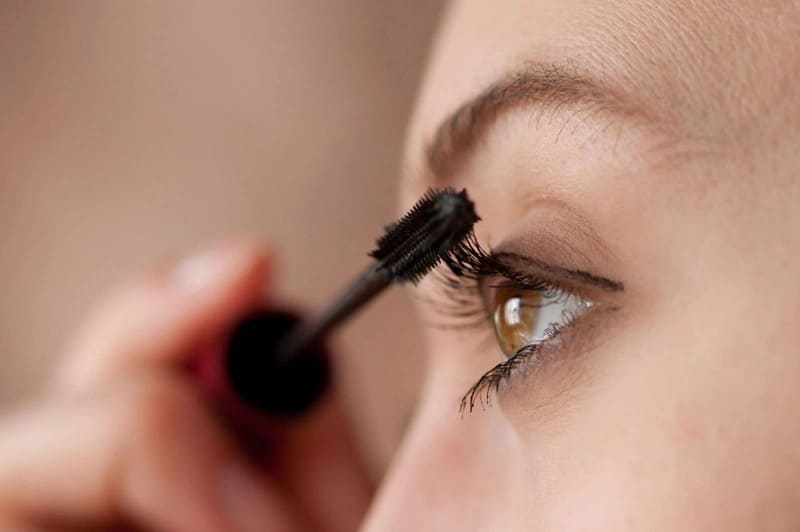 Cận cảnh một người đang chuốt mascara lên mi mắt.