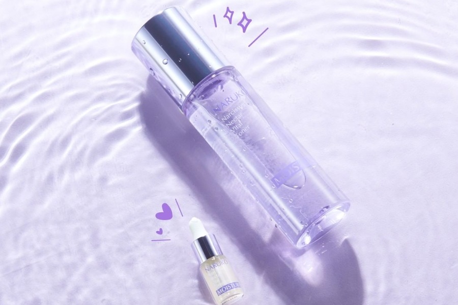 Chai toner và lọ serum nhỏ đặt trên nền màu tím với ánh sáng lung linh.