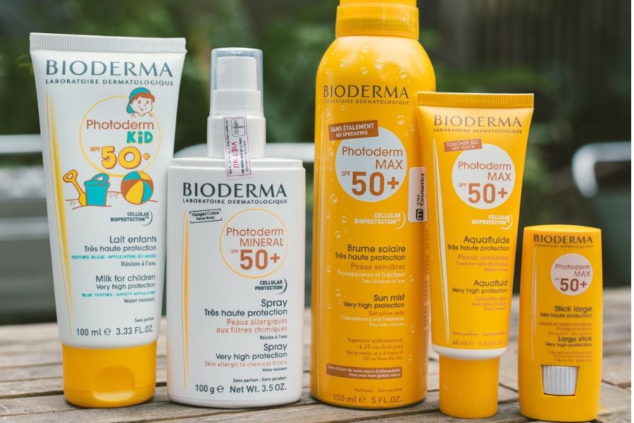 Bộ sản phẩm kem chống nắng Bioderma Photoderm SPF 50+ với nhiều loại chai và kích cỡ khác nhau trên bàn gỗ.