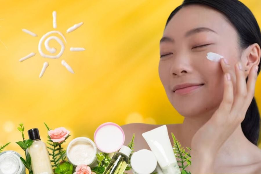 Người phụ nữ thoa kem dưỡng da mặt, nền vàng, bên cạnh các sản phẩm chăm sóc da và hình vẽ mặt trời.