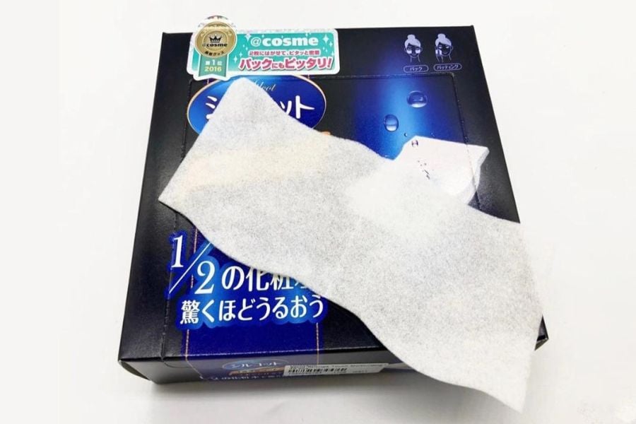 Hộp sản phẩm mỹ phẩm màu đen với miếng bông tẩy trang màu trắng đặt phía trên.