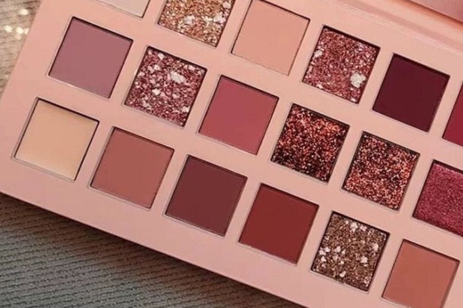 Bảng phấn mắt với nhiều ô màu khác nhau, từ tông màu nude đến ánh nhũ, sắp xếp trong một hộp hình chữ nhật.