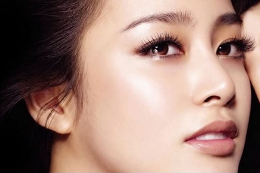 Cận cảnh khuôn mặt người với làn da mịn màng, mắt nhìn lên, đôi môi nhẹ nhàng và lông mi dài.