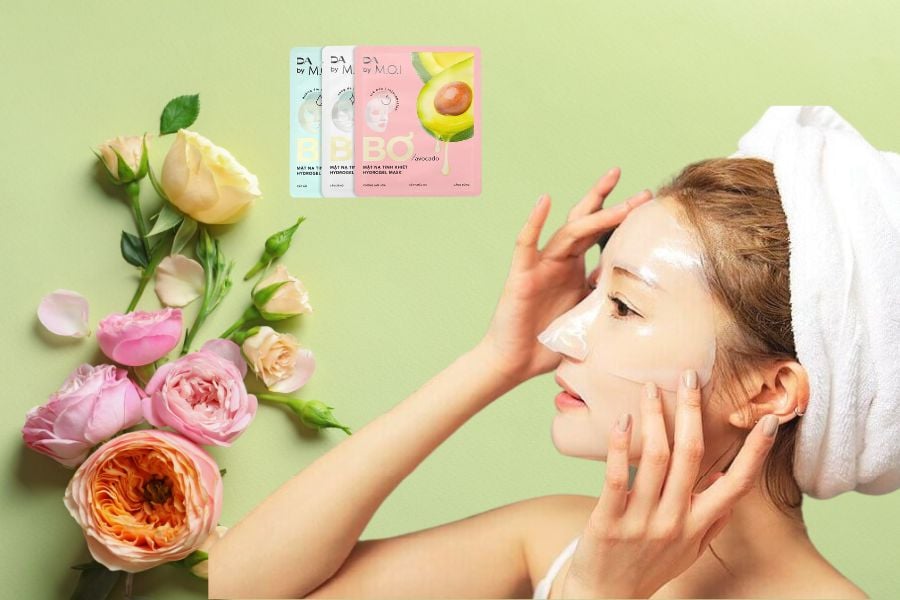 Người đắp mặt nạ dưỡng da, bên cạnh là các gói sản phẩm mặt nạ và hoa nhiều màu sắc trên nền xanh.