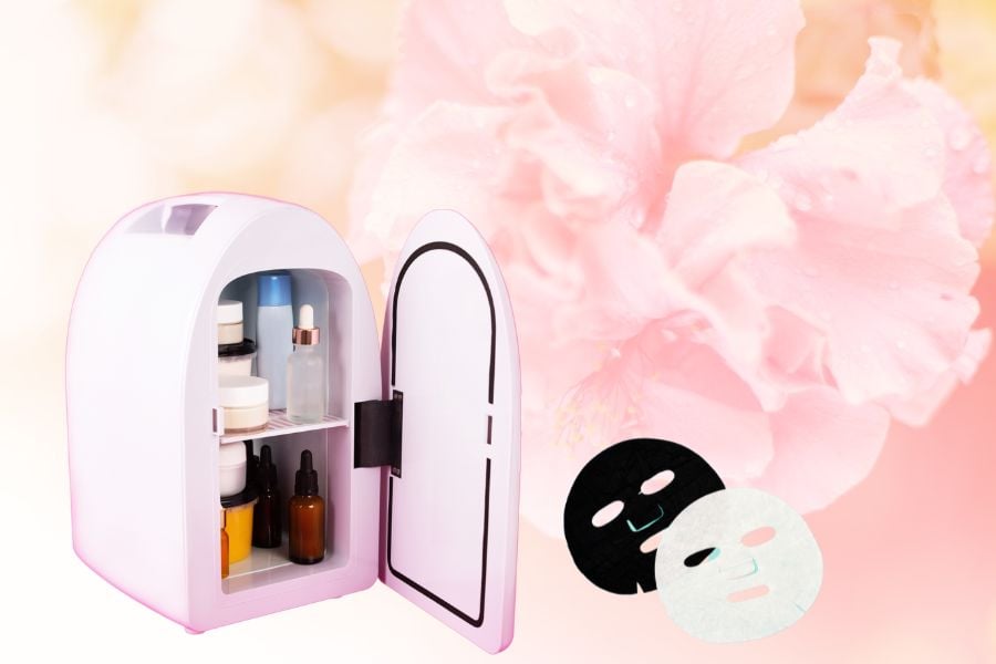 Tủ lạnh mini chứa mỹ phẩm và mặt nạ giấy màu đen, trắng, nền hoa màu hồng nhạt.