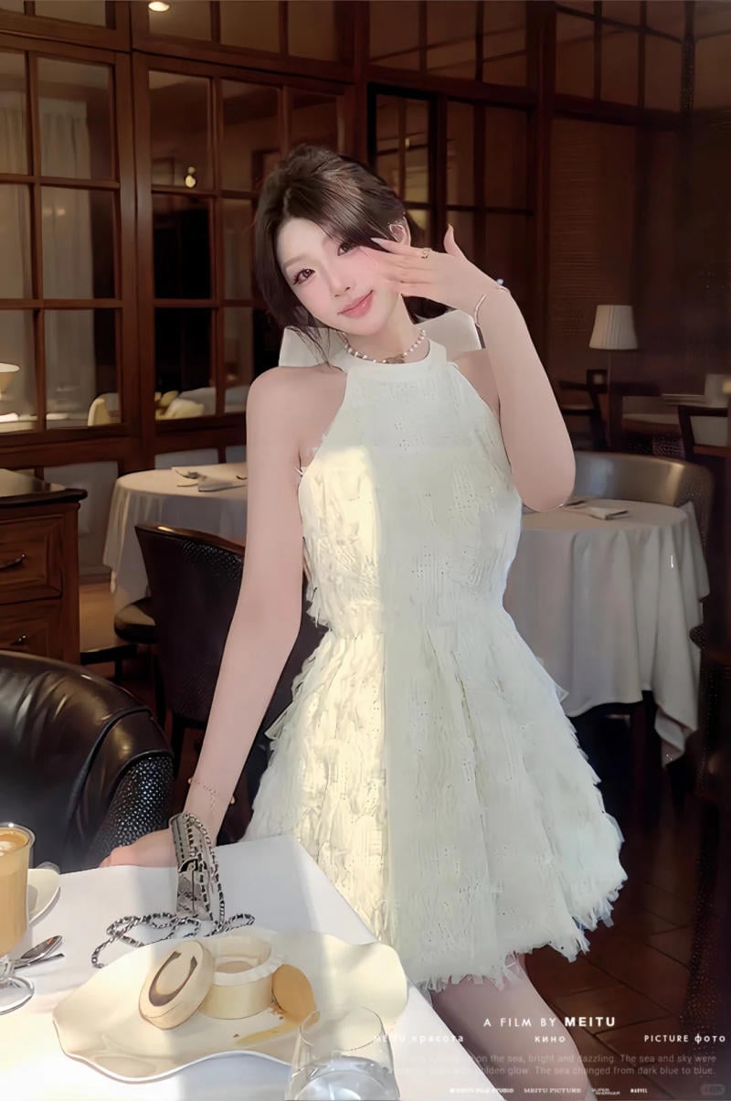 Người phụ nữ mặc váy trắng đứng cạnh bàn ăn trong một nhà hàng ấm cúng, có bánh ngọt và cà phê trên bàn.