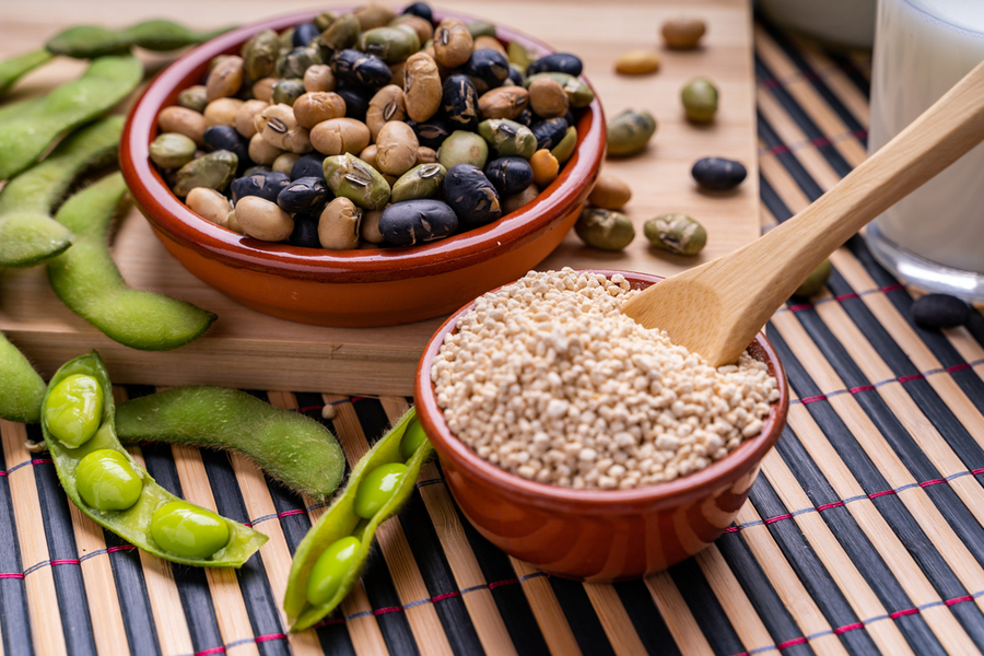 Bát đậu nành và hạt quinoa trên bàn tre, cạnh đậu nành tươi và sữa đậu nành.