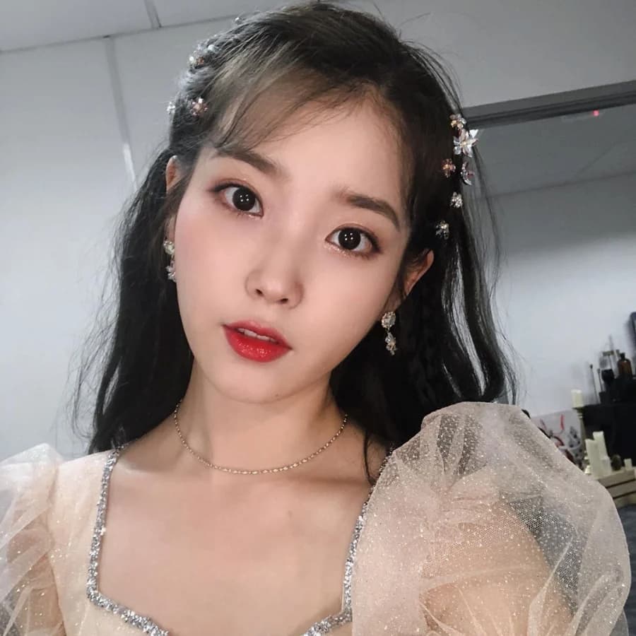 Người phụ nữ với trang phục lấp lánh và phụ kiện tóc, chụp ảnh trong nhà với ánh sáng nhẹ.