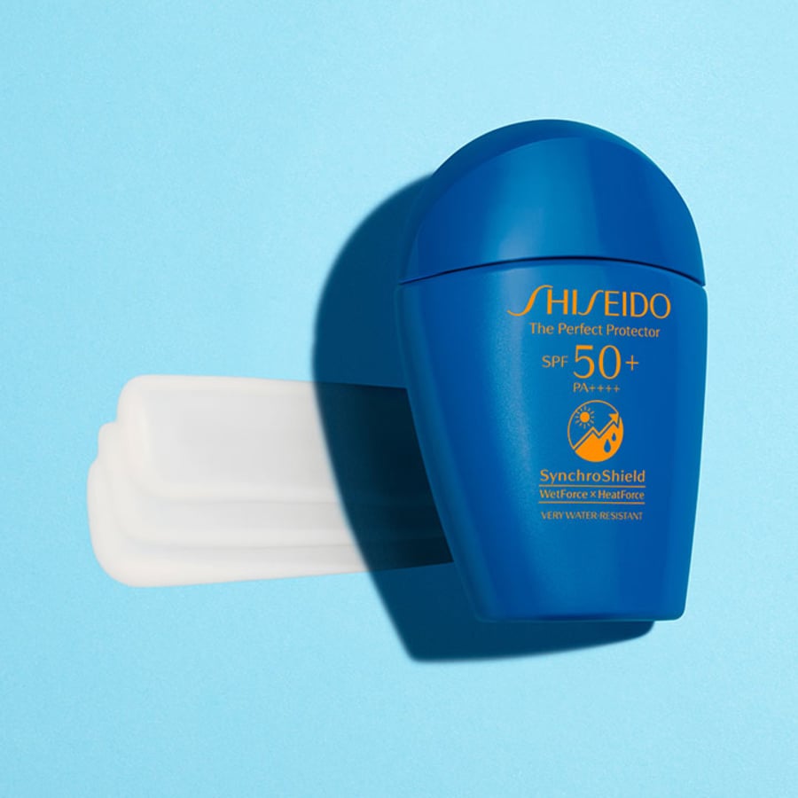 Chai kem chống nắng màu xanh, SPF 50+, nằm trên nền xanh, với một vệt kem trắng phía sau.