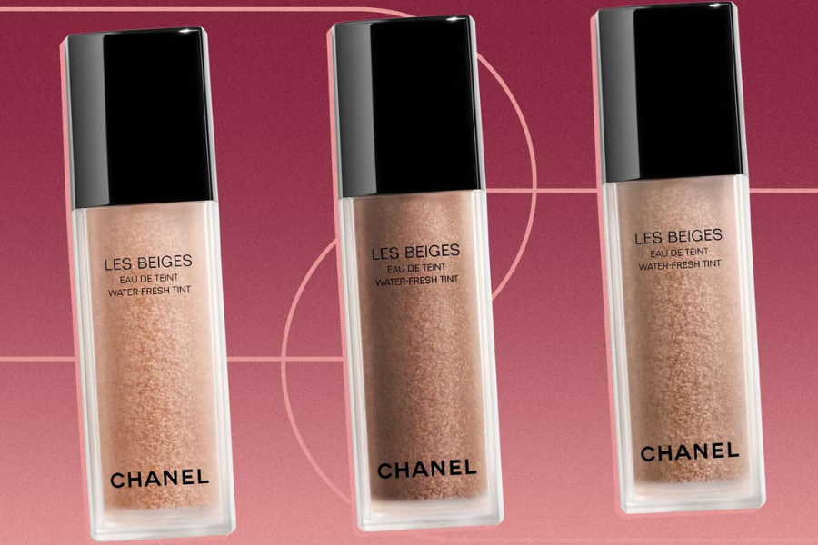 Ba chai nước tint trang điểm trên nền hồng, nhãn hiệu Chanel, có nắp màu đen và thân chai trong suốt.