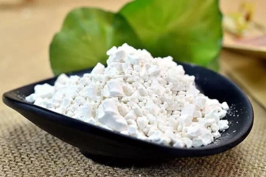 Đĩa đen chứa bột màu trắng, đặt trên bề mặt vải nâu, phông nền là lá xanh.