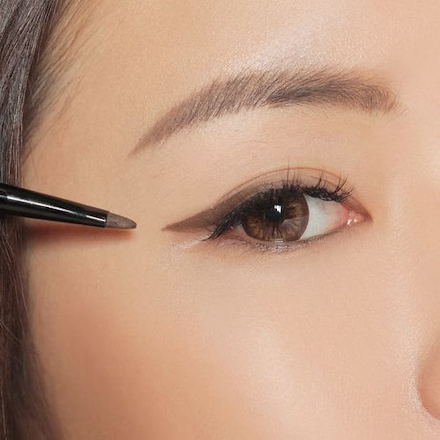 Cận cảnh mắt đang được trang điểm với bút kẻ mắt màu đen, tạo đường viền sắc nét.