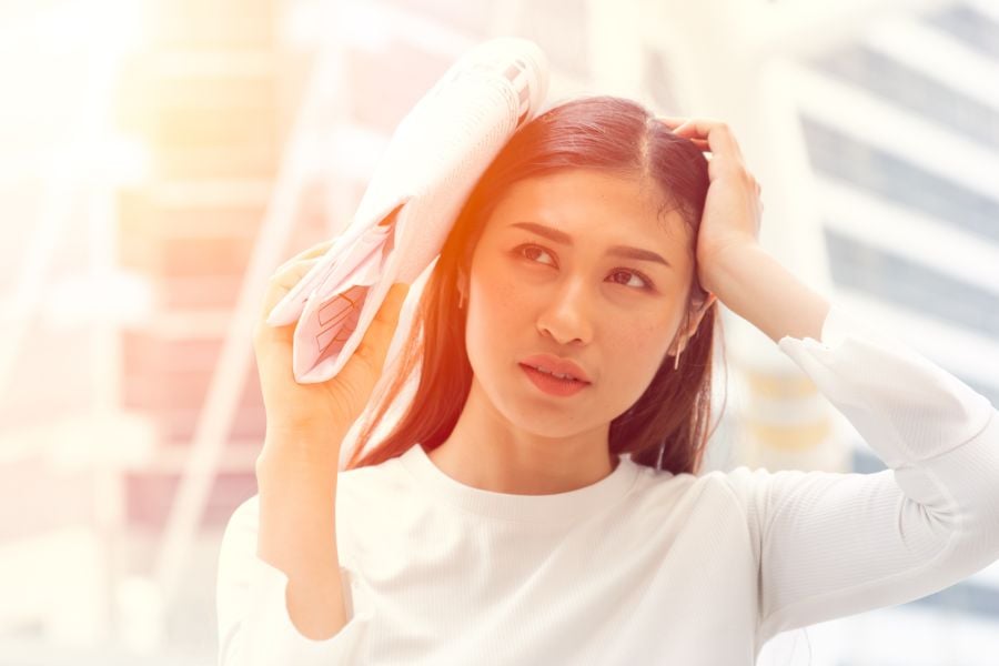 Người cầm tờ báo che tai, đứng trong không gian sáng, biểu cảm suy tư.