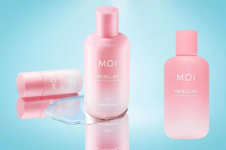 Ba chai mỹ phẩm màu hồng trên nền xanh, một chai nằm ngang với chất lỏng tràn ra.