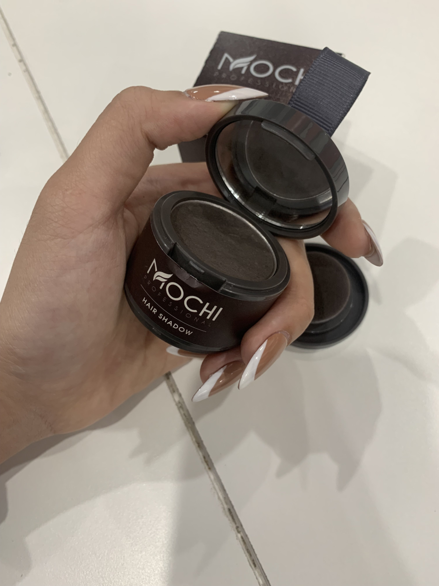 Người cầm hộp phấn mắt màu nâu, nắp mở, trên nền trắng.
