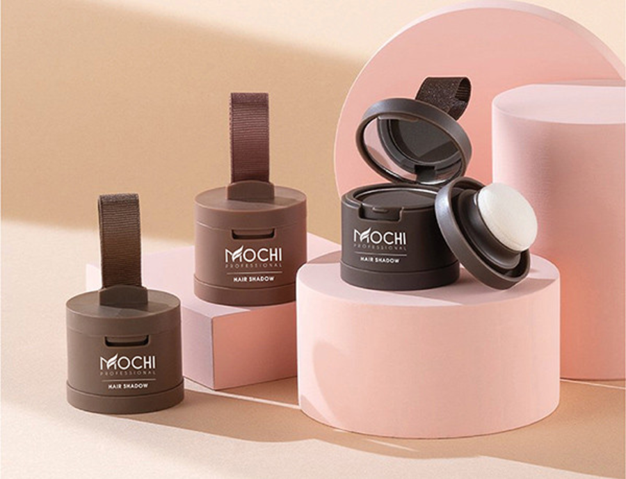 Ba hộp phấn trang điểm tóc màu nâu được đặt trên nền hồng và be, với một hộp mở nắp và bông phấn bên cạnh.