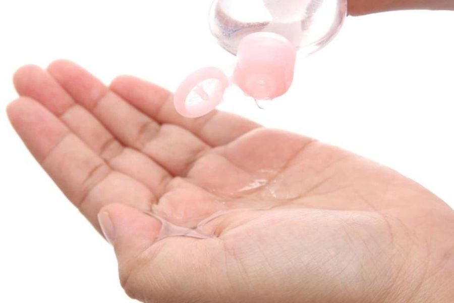 Bàn tay đang nhận dung dịch từ chai nhựa trong suốt với nắp màu hồng.
