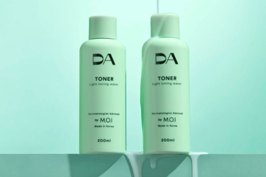 Hai chai toner màu xanh nhạt với nhãn hiệu DA, dung tích 200ml, đặt trên nền xanh.
